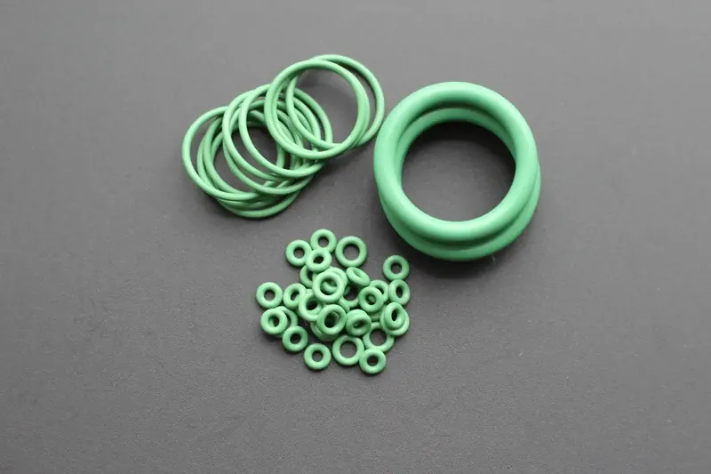 Green perfluoroelastomer O-rings in several diameters grouped on a grey background