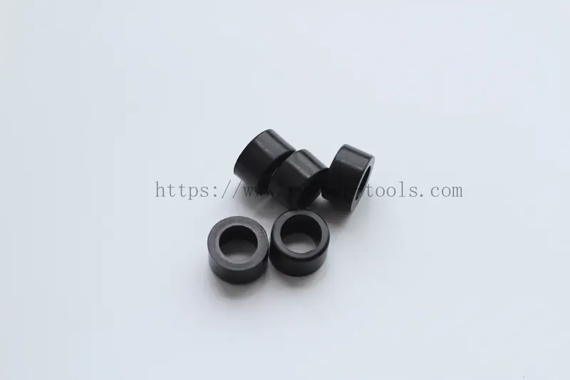 Three black moulded rubber sealing bushes standing on a light surface