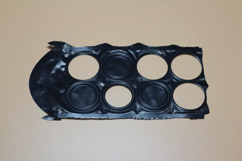 Black moulded component with multiple circular apertures resting on a light surface